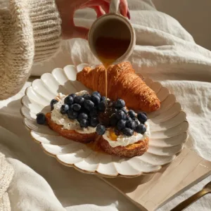 Croissant with fresh blueberries on a plate, ready to be enjoyed.