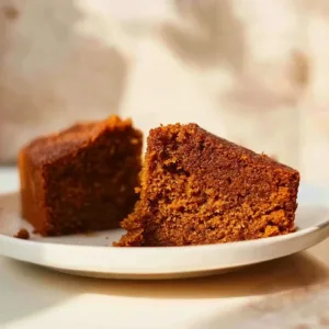 Sliced flourless oatmeal carrot cake on a plate with frosting