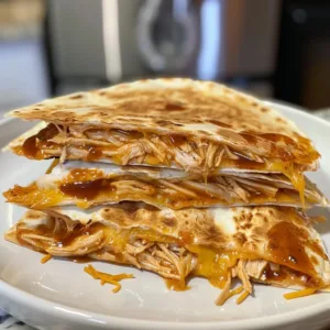 Delicious BBQ chicken quesadilla served with dipping sauce on a plate